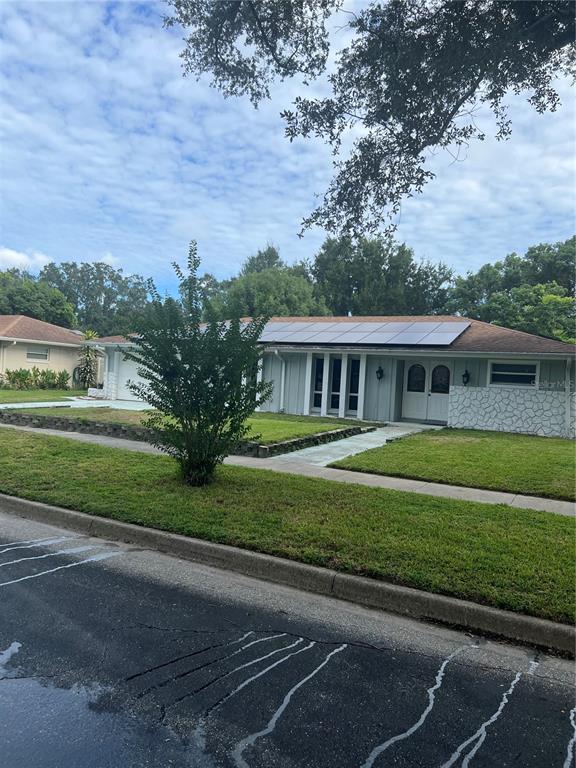 A single-story house with a light-colored facade, solar panels on the roof, and a front lawn — 5133 BRENDA DRIVE, ORLANDO, FL