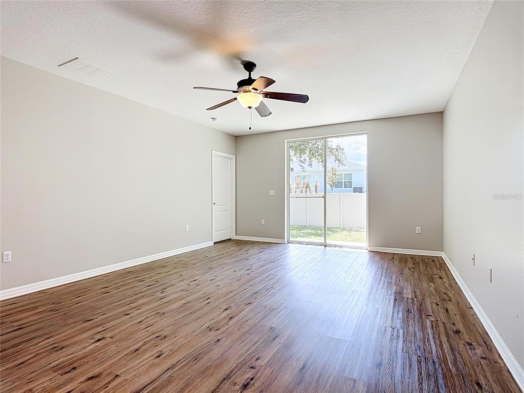 An empty room features wood-look flooring, a ceiling fan, and a sliding glass door — 1562 TAMARIND ROAD, DAVENPORT, FL