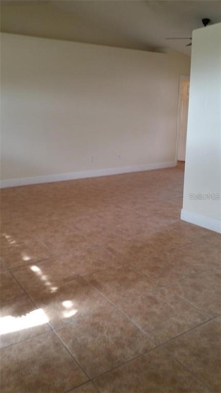 An empty room features light-colored walls and brown tiled flooring — 503 PINE BARK COURT, KISSIMMEE, FL