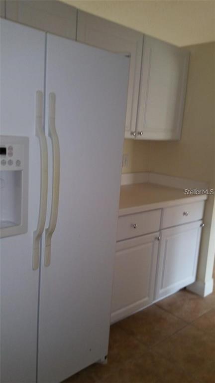 A white refrigerator stands next to white kitchen cabinets and a countertop — 503 PINE BARK COURT, KISSIMMEE, FL