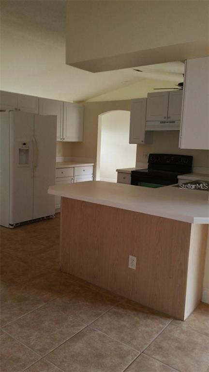 A kitchen features white cabinets, a white refrigerator, a breakfast bar, and tiled flooring — 503 PINE BARK COURT, KISSIMMEE, FL