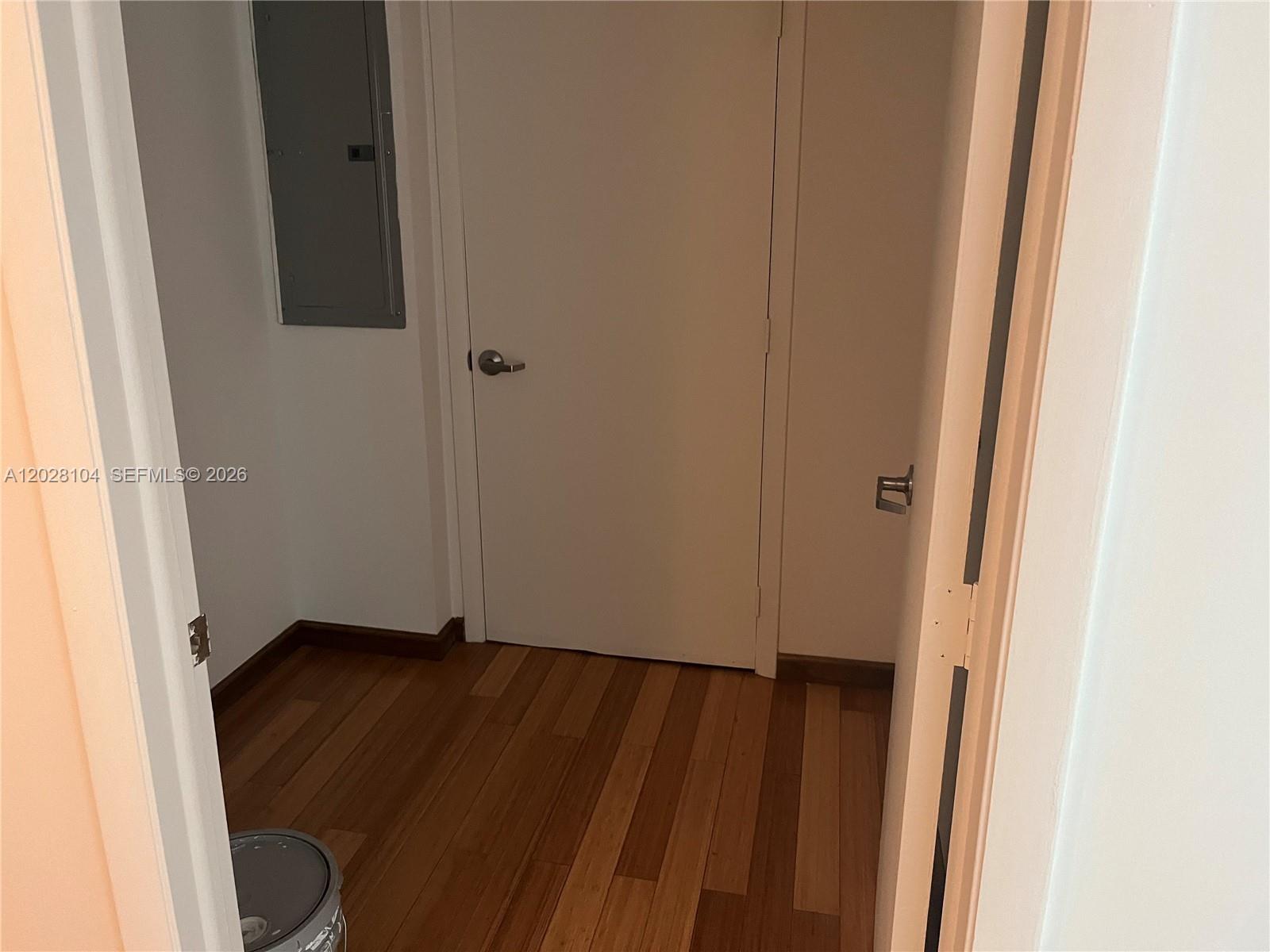 A small hallway features hardwood floors, a closed white door, and a wall-mounted electrical panel — 1800 N Bayshore Dr # 915, Miami FL 33132, MIAMI, FL