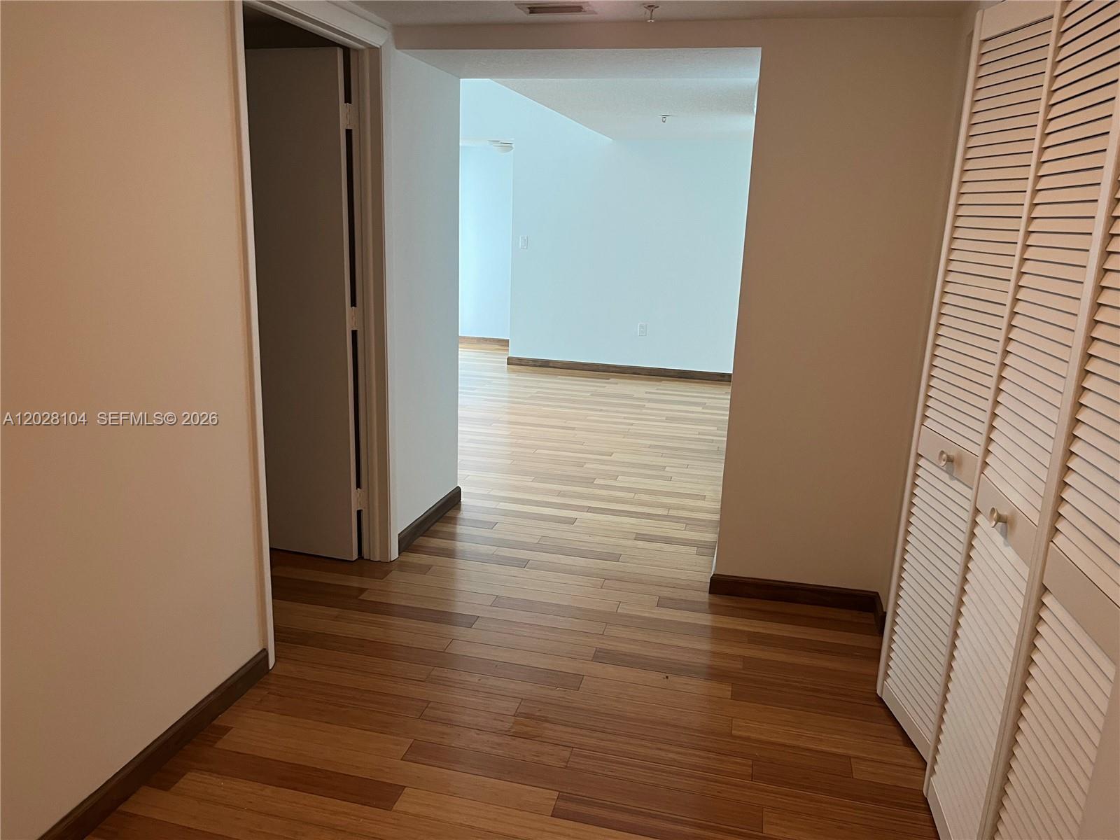A hallway with wood-look flooring leads to an open living area with white walls — 1800 N Bayshore Dr # 915, Miami FL 33132, MIAMI, FL