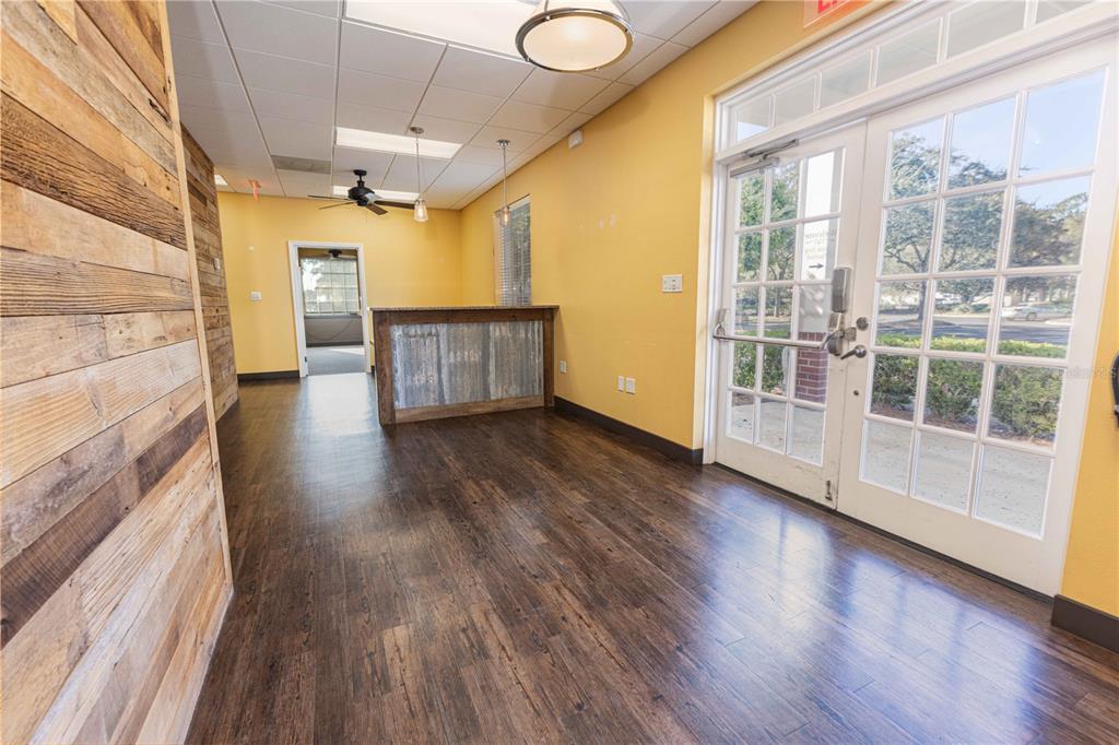 An office interior with wood-paneled walls, dark wood flooring, a reception desk, and glass doors — 3400 SOUTHERN TRACE, THE VILLAGES, FL
