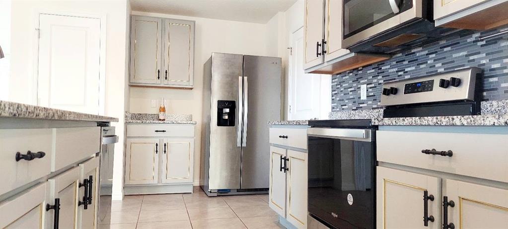 A kitchen features light-colored cabinets with gold trim, stainless steel appliances, and granite countertops — 35386 SPRUCE KNOB COURT, DADE CITY, FL