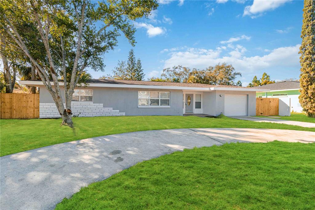 A single-story gray house with a white brick accent wall, garage, and curved concrete driveway — 540 MILWAUKEE AVENUE, DUNEDIN, FL