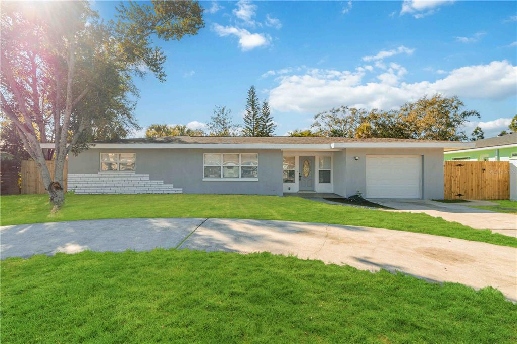 A single-story gray house with a white brick accent, a garage, and a curved driveway — 540 MILWAUKEE AVENUE, DUNEDIN, FL