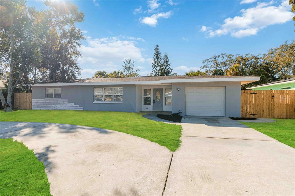 A single-story gray house with a white brick accent, a garage, and a concrete driveway — 540 MILWAUKEE AVENUE, DUNEDIN, FL