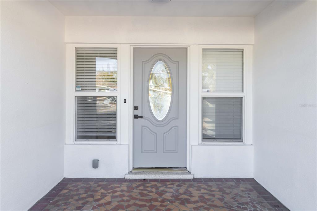 A gray front door with an oval glass insert is flanked by two windows — 540 MILWAUKEE AVENUE, DUNEDIN, FL