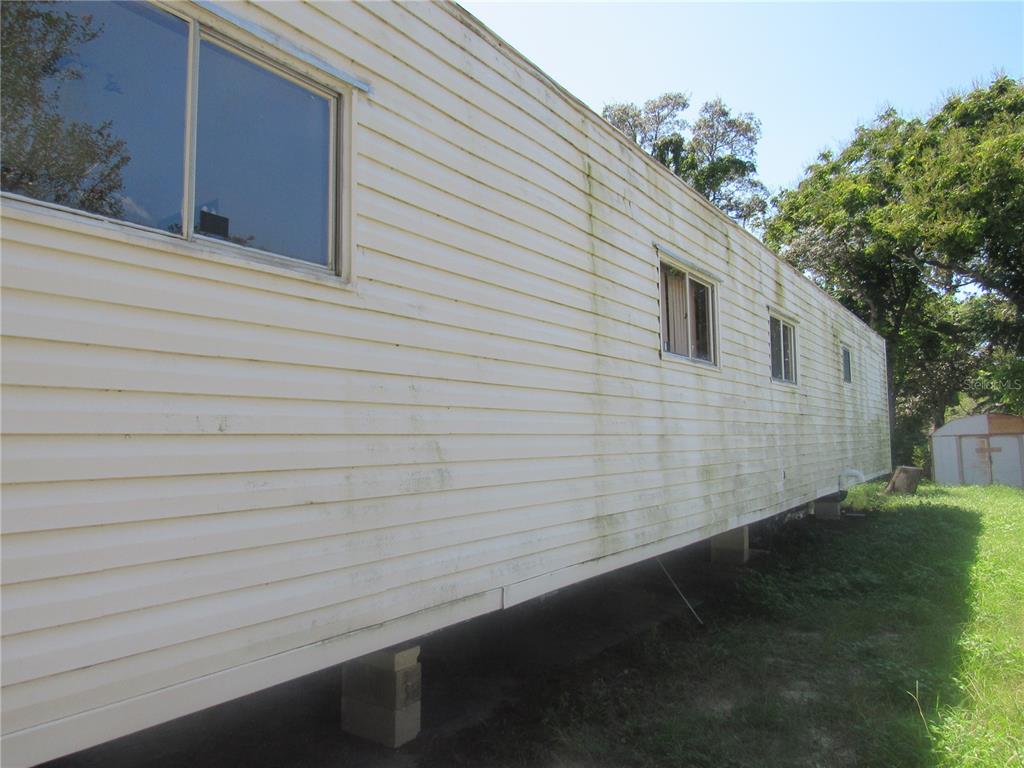 The exterior side of a mobile home features light-colored horizontal siding and several windows — 1950 SE 185TH TERRACE, SILVER SPRINGS, FL