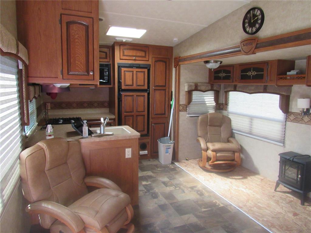 A kitchen and living area in a recreational vehicle featuring wood cabinetry and two chairs — 1950 SE 185TH TERRACE, SILVER SPRINGS, FL