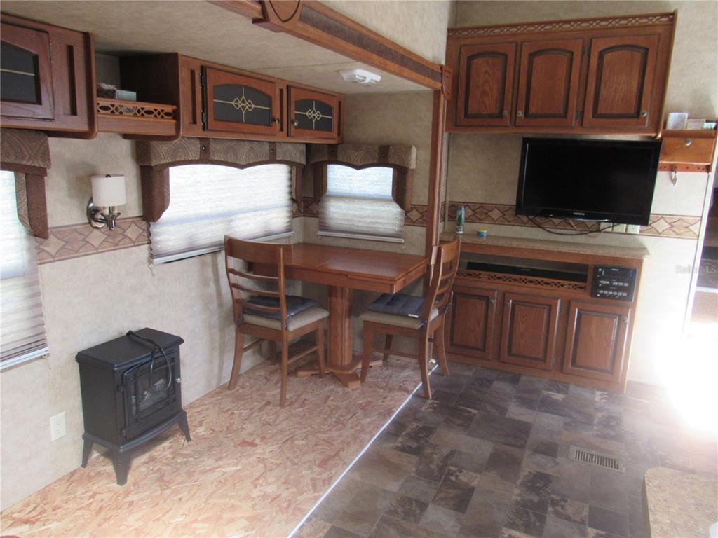 An RV interior features a dining table, chairs, a television, and a small electric fireplace — 1950 SE 185TH TERRACE, SILVER SPRINGS, FL