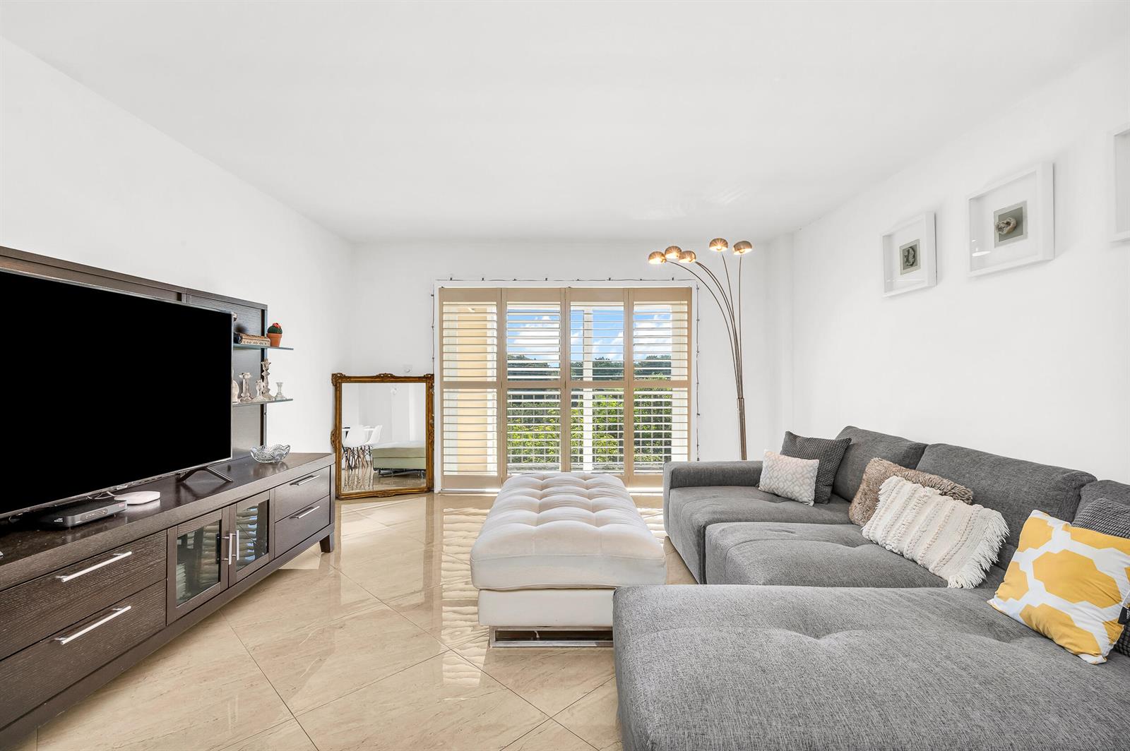 A living room features a grey sectional sofa, a white ottoman, and large sliding glass doors — 1111 S Ocean Boulevard # 420, Boca Raton FL 33432, BOCA RATON, FL
