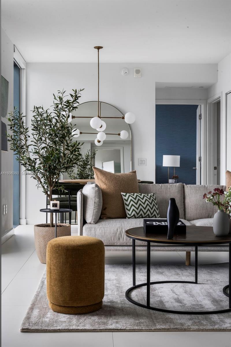 A modern living room features a grey sofa, a round coffee table, and an arched mirror — 501 NE 31st St # 3409, Miami FL 33137, MIAMI, FL