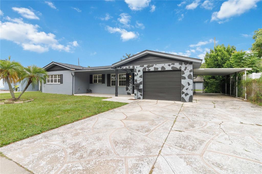 A single-story house with a gray brick exterior, stone-accented garage, and a concrete driveway — 1115 S ALDER AVENUE, ORLANDO, FL