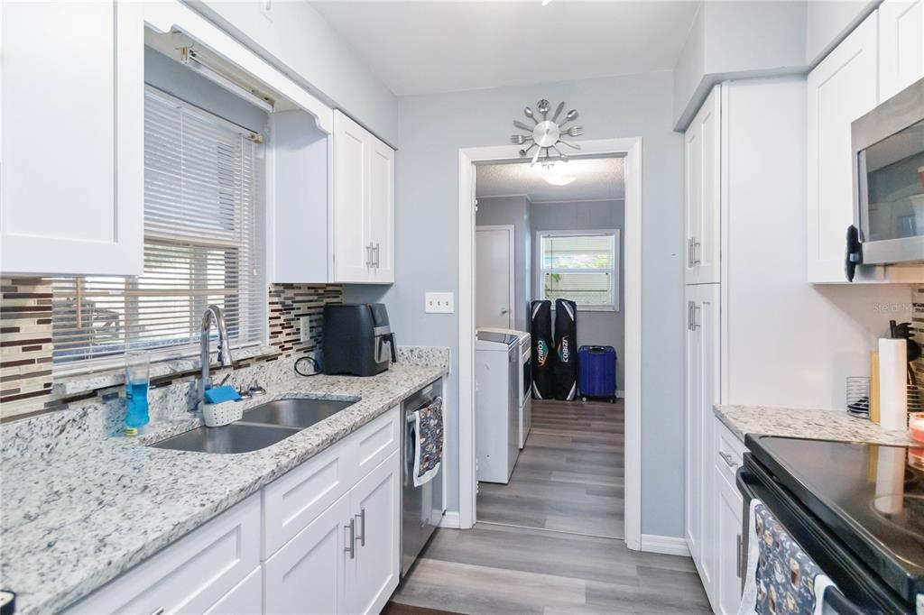 A kitchen with white cabinets, granite countertops, and a doorway leading to a laundry room — 1115 S ALDER AVENUE, ORLANDO, FL