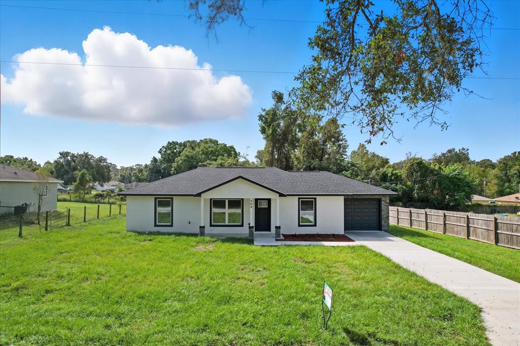 A single-story house with a white exterior, dark roof, and a concrete driveway — 19857 SW FLAMINGO DRIVE, DUNNELLON, FL