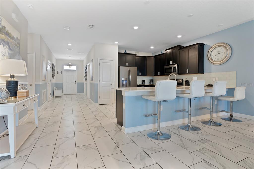 A kitchen with dark cabinets and a breakfast bar overlooks a tiled entryway — 1613 MAIDSTONE COURT, DAVENPORT, FL