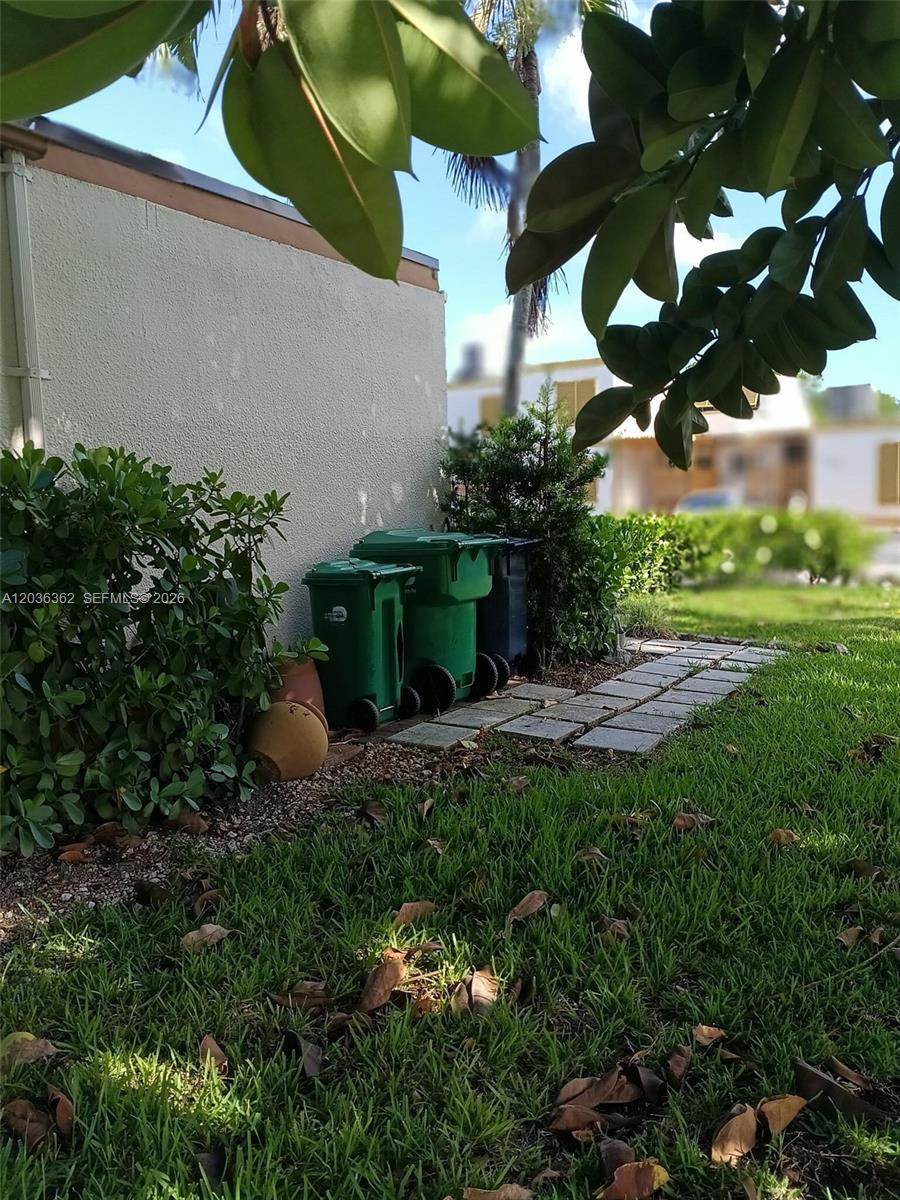 An exterior view shows three trash bins sitting on a stone path beside a building — 1700 SW 131st Place Cir S, Miami FL 33175, MIAMI, FL