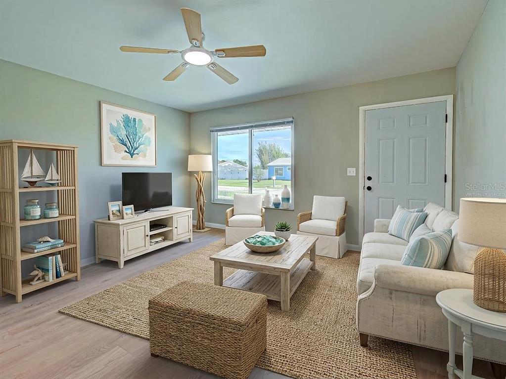 A living room features light green walls, a jute rug, coastal decor, and a ceiling fan — 6837 KETONA ROAD, NORTH PORT, FL
