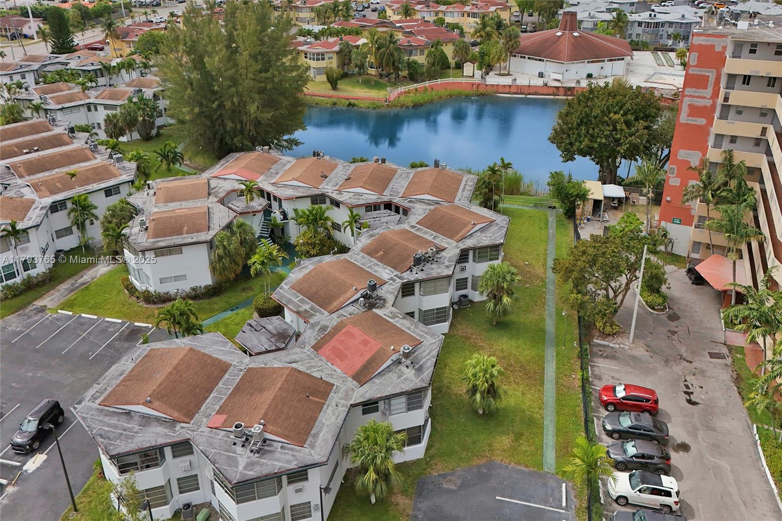 An aerial view shows a multi-unit residential complex with brown roofs near a lake — 18746 NE 18th Ave # 146, Miami FL 33179, MIAMI, FL