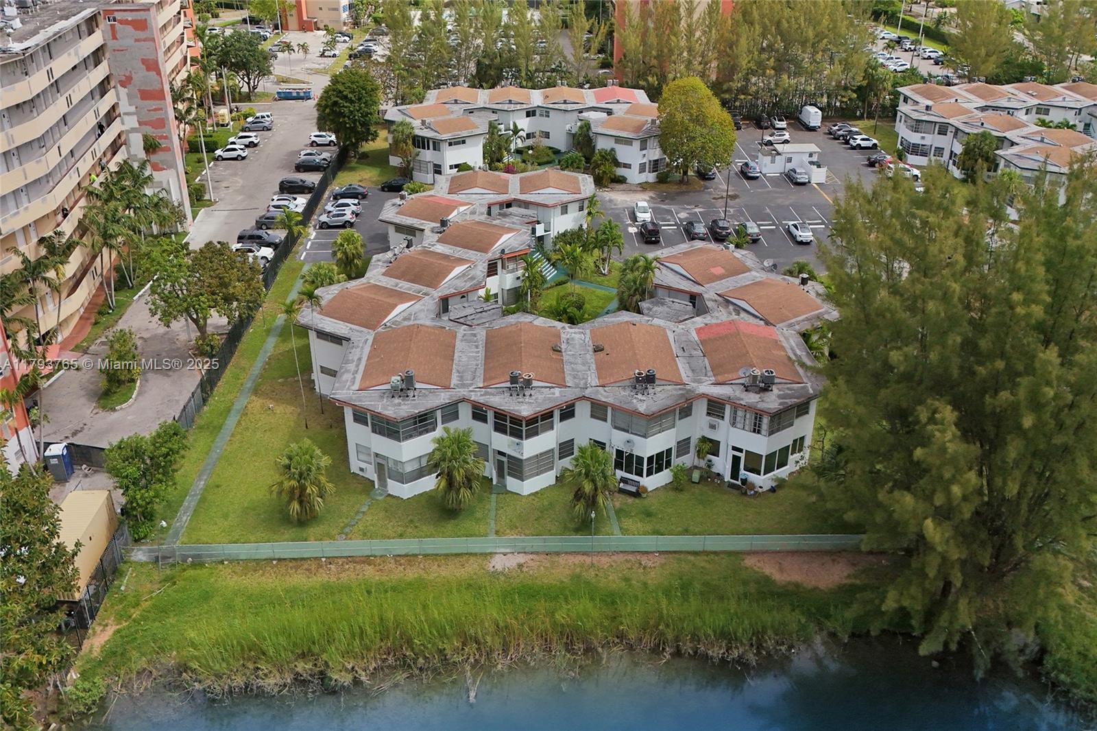 An aerial view shows a multi-unit residential building with brown roofs next to a canal — 18746 NE 18th Ave # 146, Miami FL 33179, MIAMI, FL