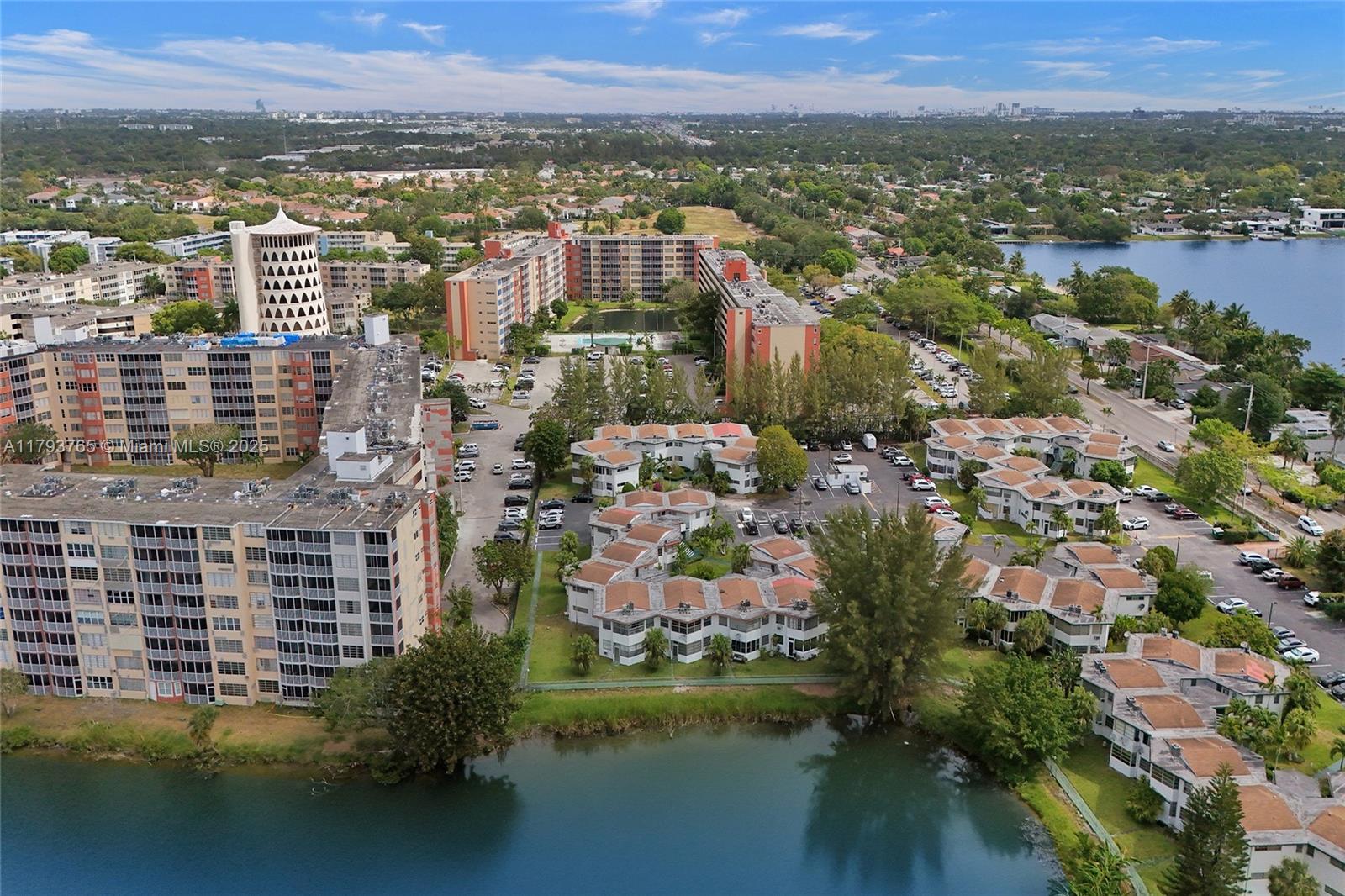 An aerial view shows apartment buildings and townhomes situated near a lake and parking lots — 18746 NE 18th Ave # 146, Miami FL 33179, MIAMI, FL