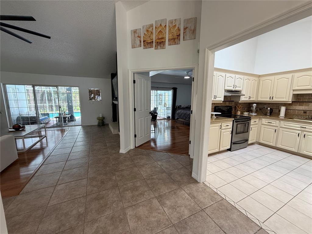 A tiled entryway leads to a kitchen with cream cabinets and a view of a bedroom — 77 CIMMARON DRIVE, PALM COAST, FL