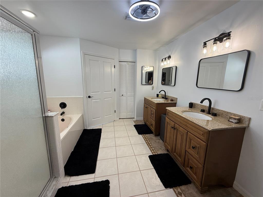 A bathroom features two wood vanities with granite countertops, a soaking tub, and tiled floors — 77 CIMMARON DRIVE, PALM COAST, FL