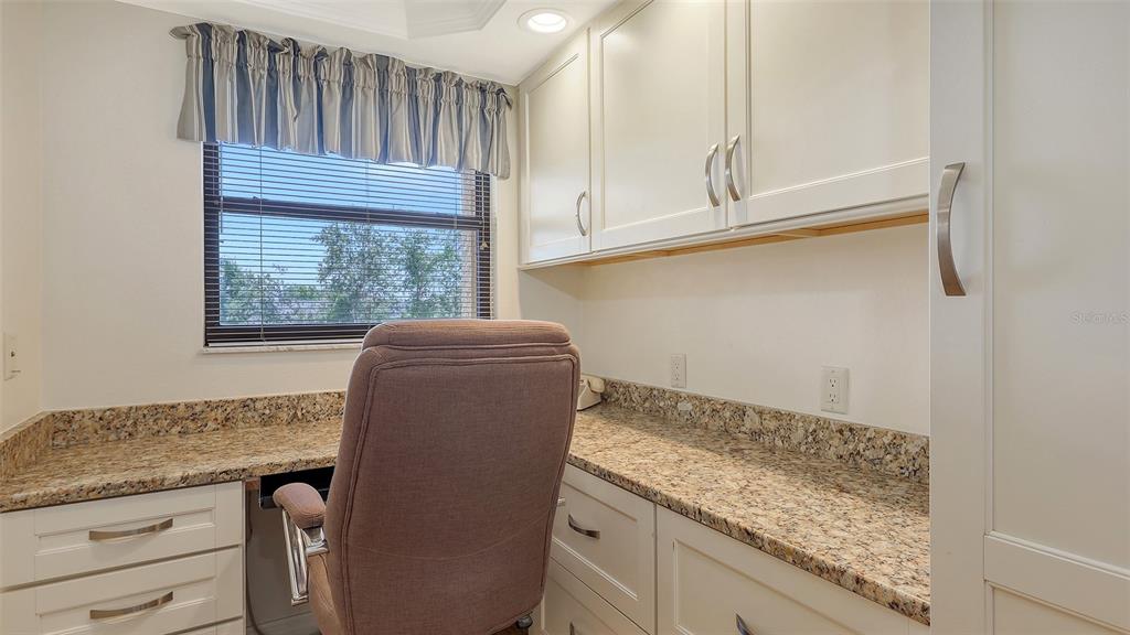 A home office features granite countertops, white cabinetry, a desk chair, and a window with blinds — 8779 MIDNIGHT PASS ROAD UNIT 401H, SARASOTA, FL