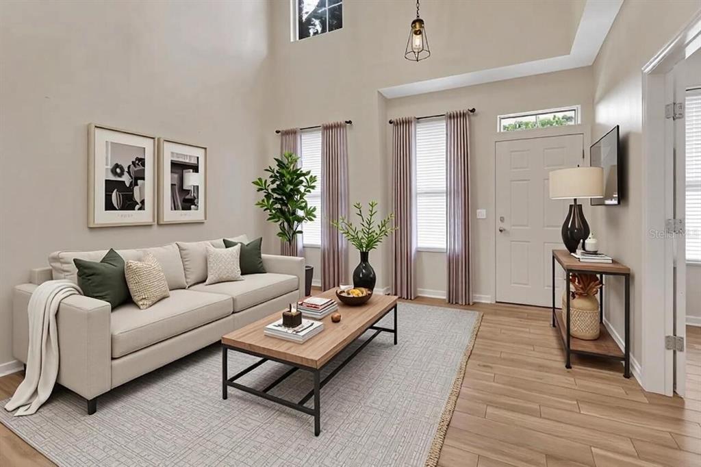 A living room with high ceilings, a beige sofa, a coffee table, and wood flooring — 204 WOODHOUSE LANE, DELAND, FL