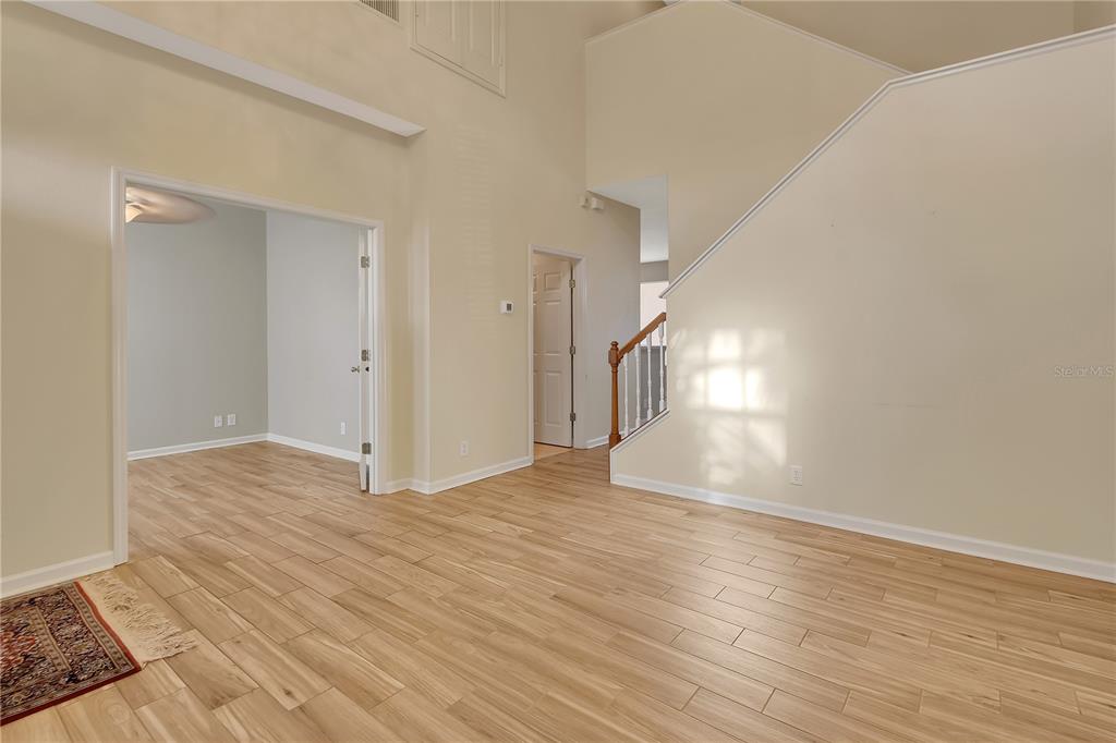 An interior view shows a foyer with light wood-look flooring, a staircase, and double doors — 204 WOODHOUSE LANE, DELAND, FL