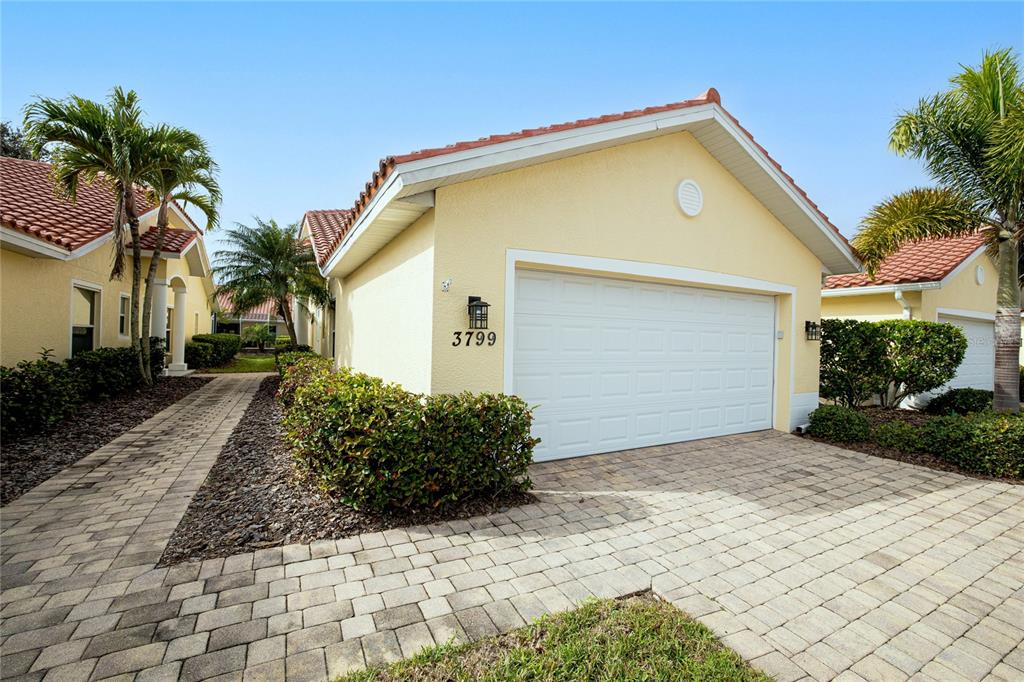 A yellow house with a white garage door, tile roof, and paved driveway — 3799 ALBACETE CIRCLE UNIT 65, PUNTA GORDA, FL