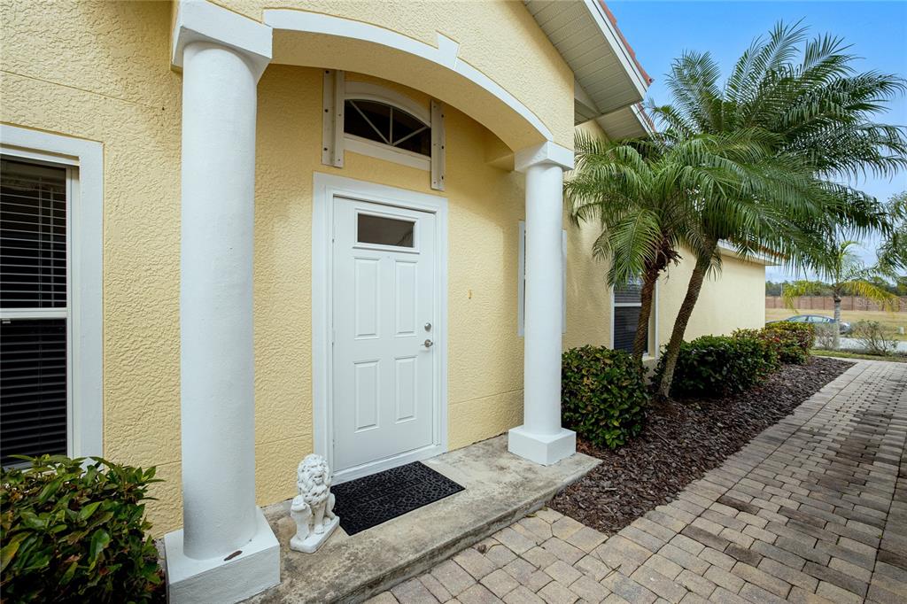 A yellow stucco house entrance features a white front door flanked by two white columns — 3799 ALBACETE CIRCLE UNIT 65, PUNTA GORDA, FL