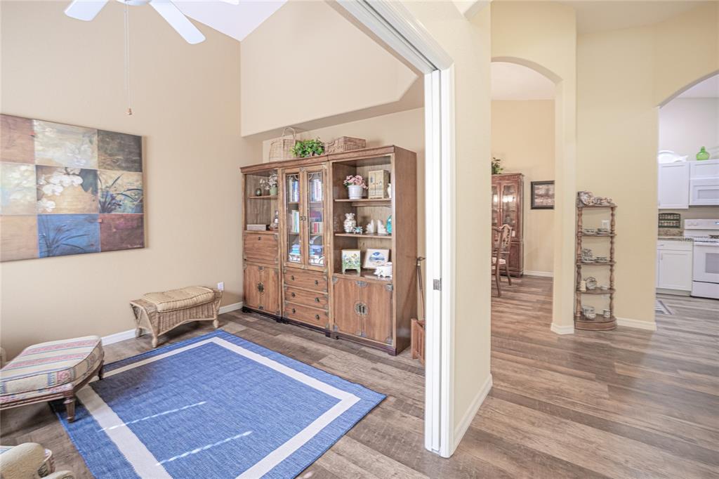 A room with a blue area rug, wooden hutch, and wicker bench leads to a kitchen — 3799 ALBACETE CIRCLE UNIT 65, PUNTA GORDA, FL
