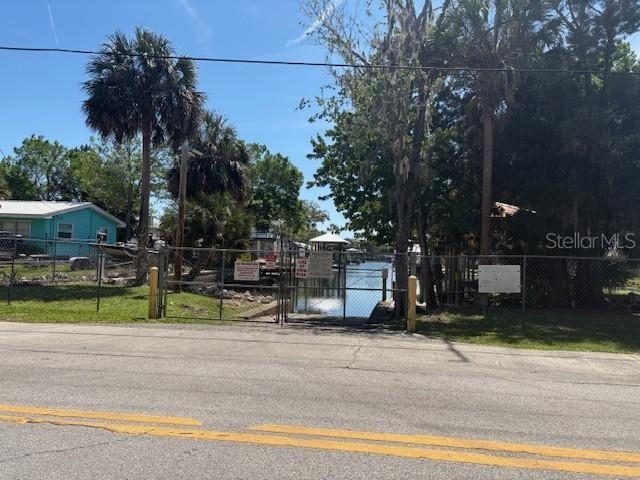A fenced-in boat canal entrance is visible from a paved road with palm trees nearby — 1541 NW 21ST STREET, CRYSTAL RIVER, FL