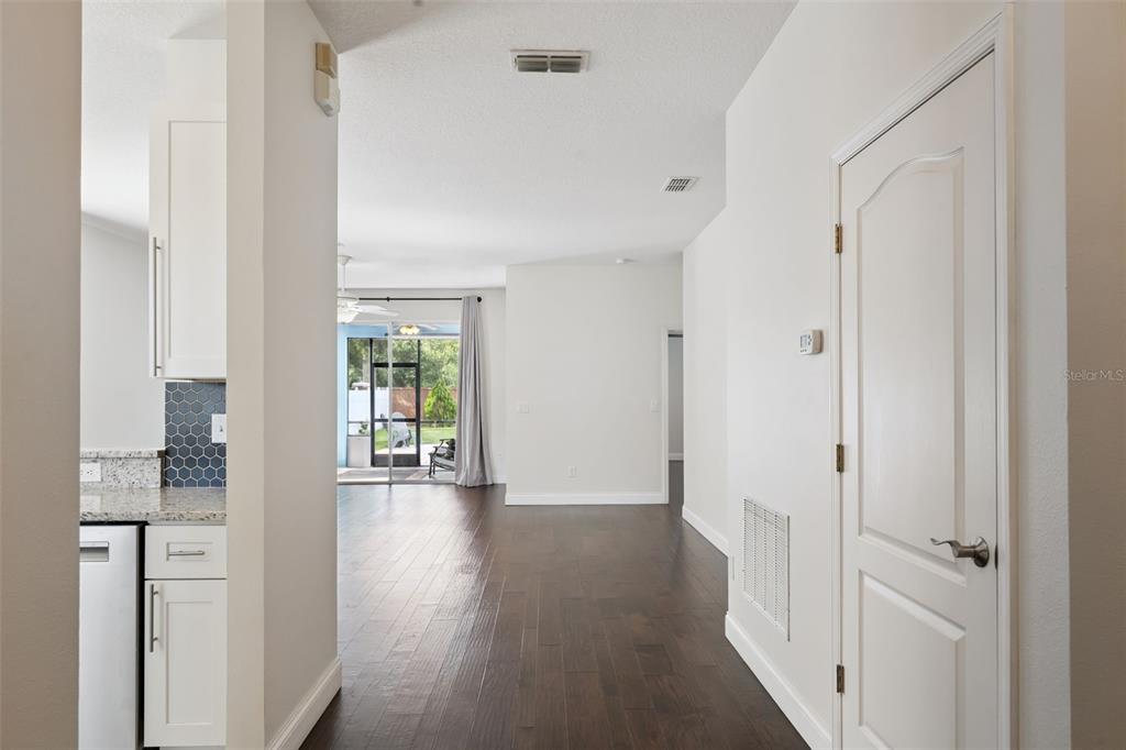 A view from a kitchen looking toward a living area with dark wood flooring — 1008 MAGNOLIA BLOSSOM COURT, APOPKA, FL