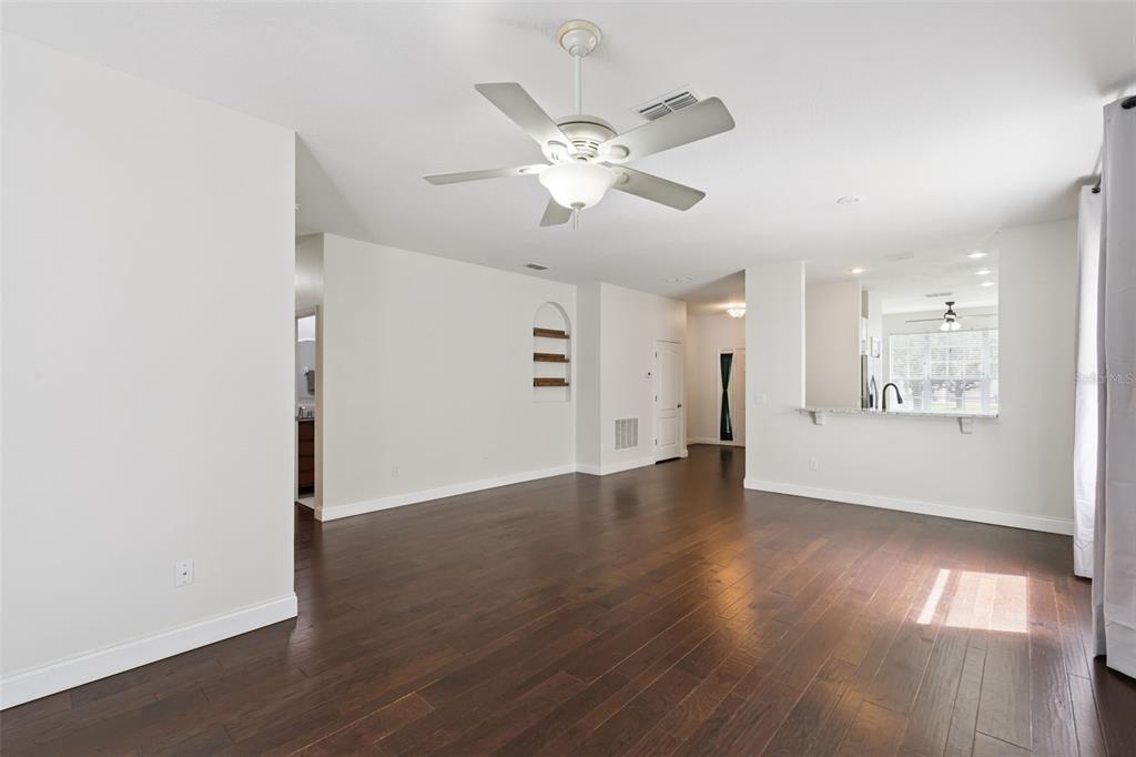 A bright living room features dark hardwood floors, a ceiling fan, and a kitchen pass-through — 1008 MAGNOLIA BLOSSOM COURT, APOPKA, FL