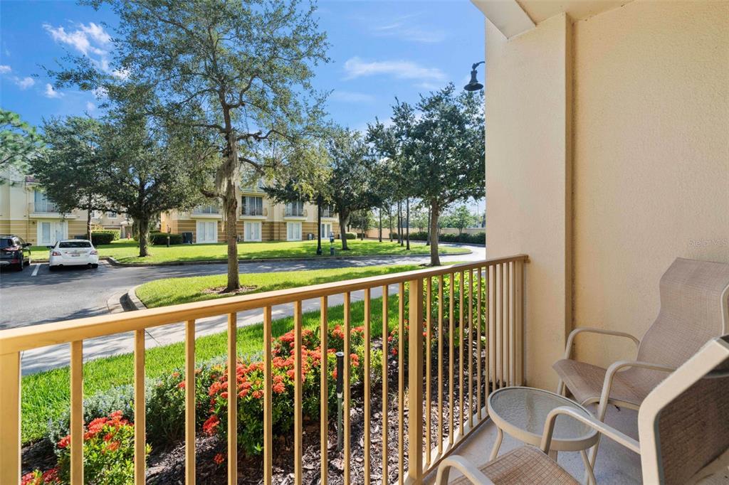 A balcony with a metal railing overlooks a parking lot, green lawn, and trees — 4802 CAYVIEW AVENUE UNIT 10814, ORLANDO, FL