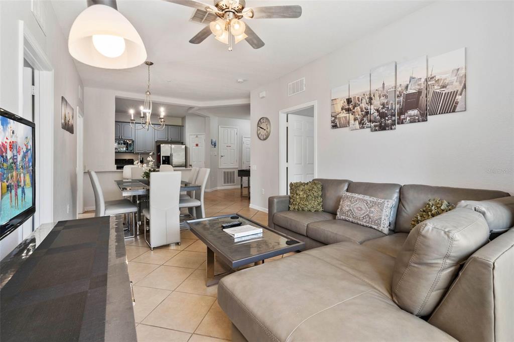 A living room features a grey sectional sofa, a coffee table, and an adjacent dining area — 4802 CAYVIEW AVENUE UNIT 10814, ORLANDO, FL