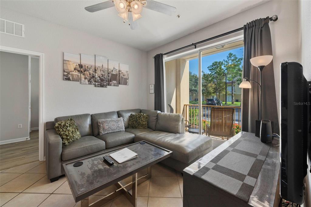 A living room features a grey sectional sofa, a coffee table, and a sliding glass door — 4802 CAYVIEW AVENUE UNIT 10814, ORLANDO, FL