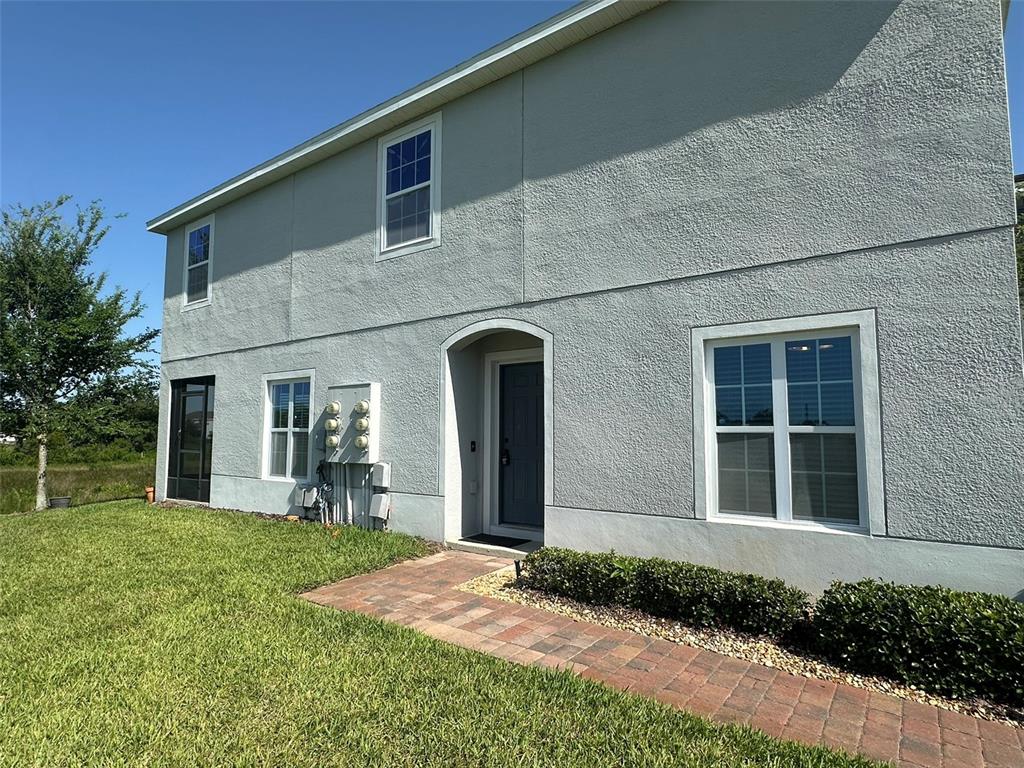 A two-story house with a gray stucco exterior, a brick walkway, and a front entrance — 172 PRIMROSE DRIVE, DAVENPORT, FL