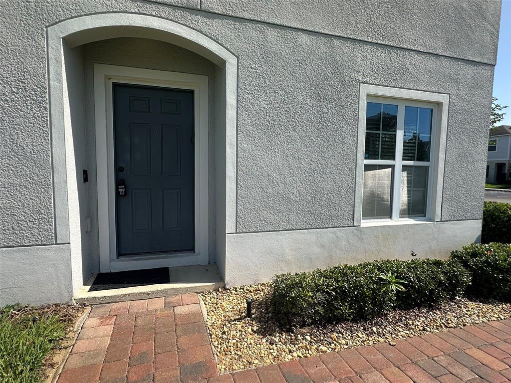 A gray front door and a window are set into the stucco exterior of a house — 172 PRIMROSE DRIVE, DAVENPORT, FL