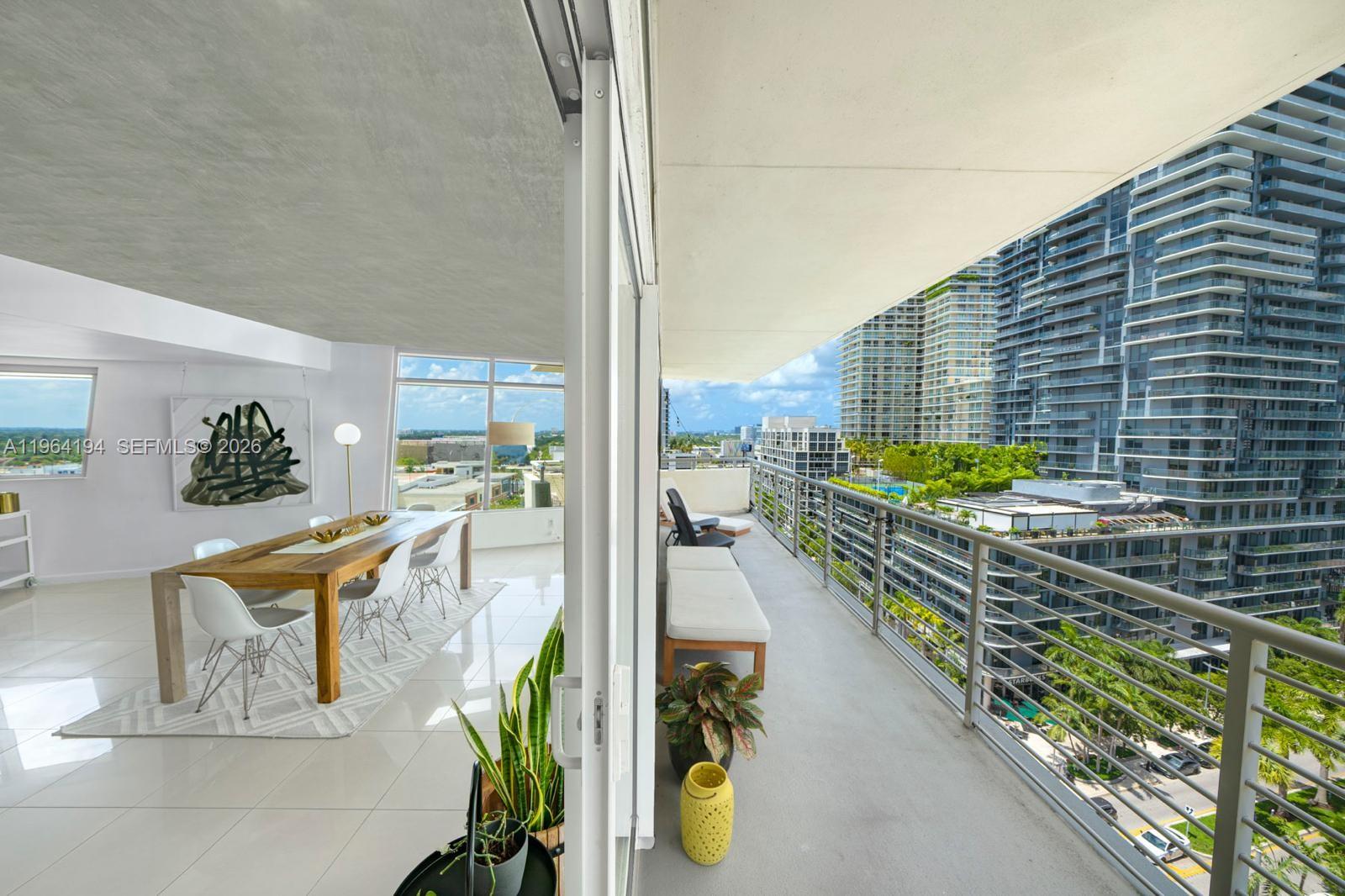 A dining area with a wooden table opens onto a long balcony overlooking city skyscrapers — 3250 NE 1st Ave # 1104, Miami FL 33137, MIAMI, FL