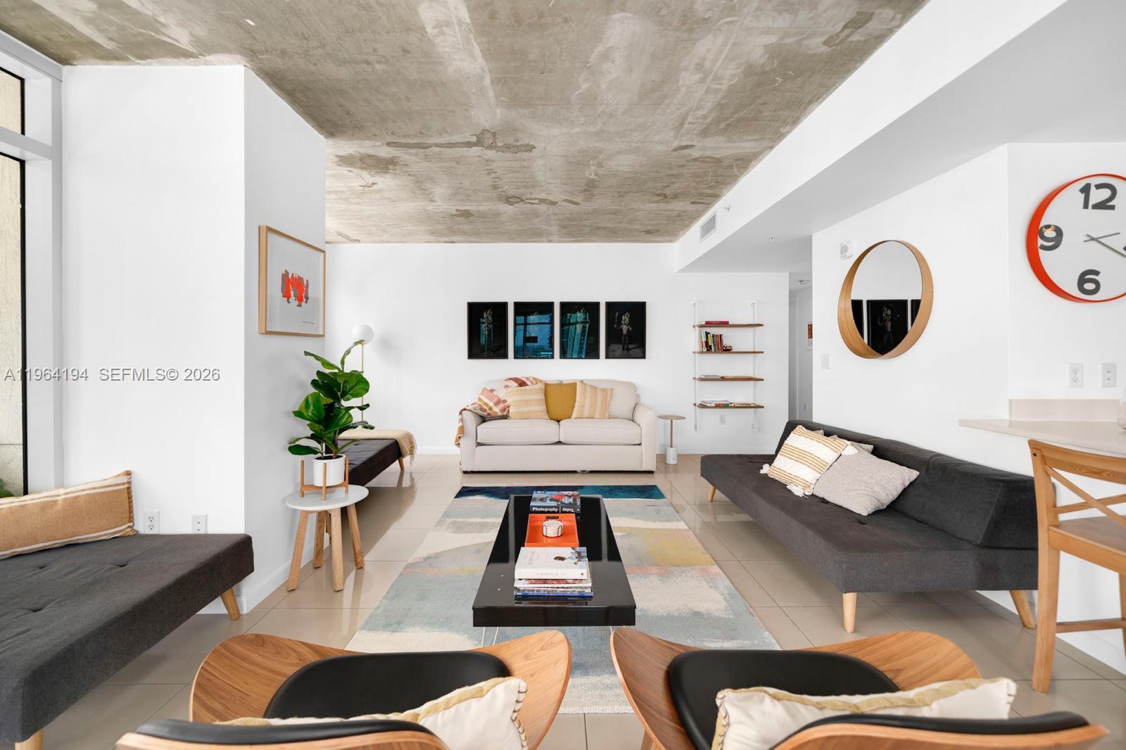 A modern living room features a concrete ceiling, white walls, and two gray sofas — 3250 NE 1st Ave # 1104, Miami FL 33137, MIAMI, FL