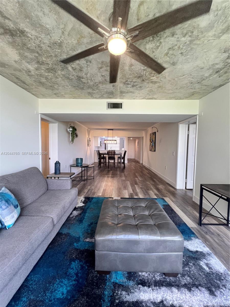 A living room with a gray sofa and ottoman leads into a dining area — 1705 Whitehall Dr # 403, Davie FL 33324, DAVIE, FL