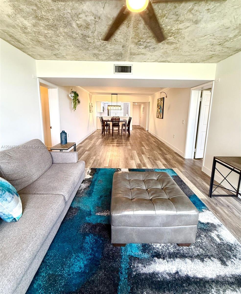A living room with a grey sofa and ottoman leads to a dining area — 1705 Whitehall Dr # 403, Davie FL 33324, DAVIE, FL