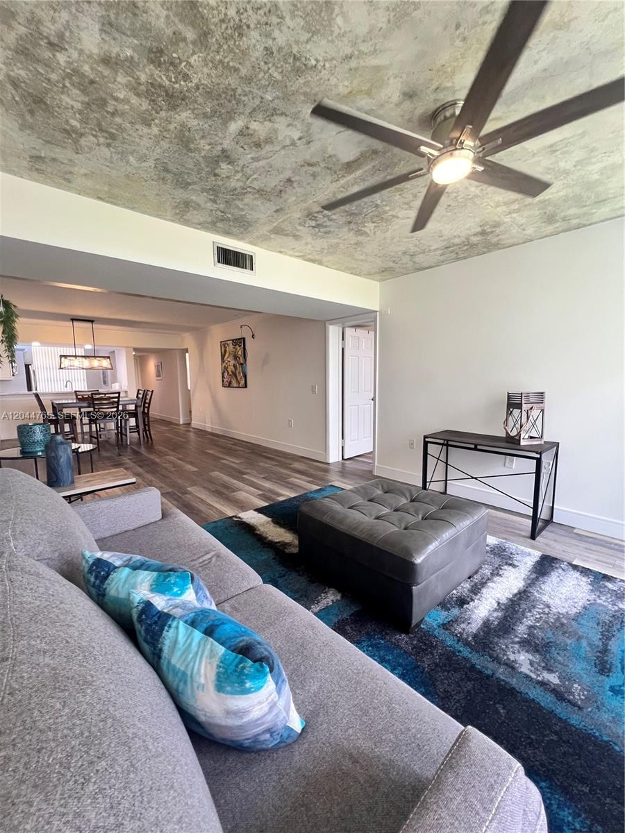 A living room features a textured ceiling, a ceiling fan, and a blue patterned rug — 1705 Whitehall Dr # 403, Davie FL 33324, DAVIE, FL