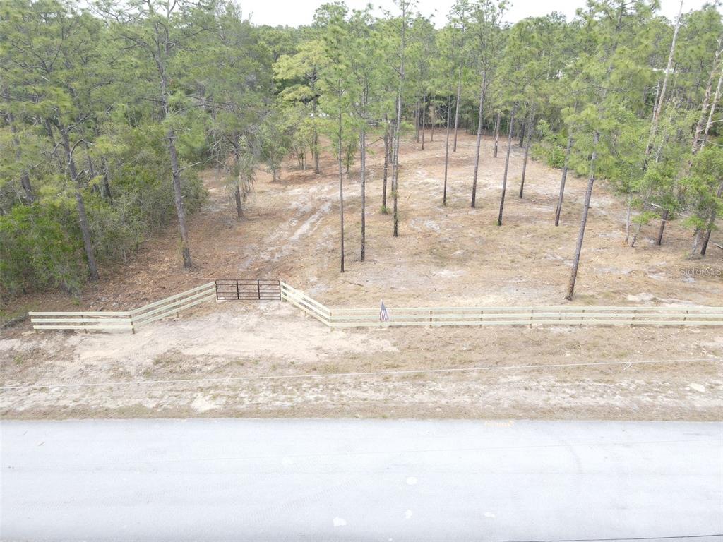 An aerial view shows a fenced, wooded lot with a gate along a paved road — SW EDGEWATER BOULEVARD, DUNNELLON, FL