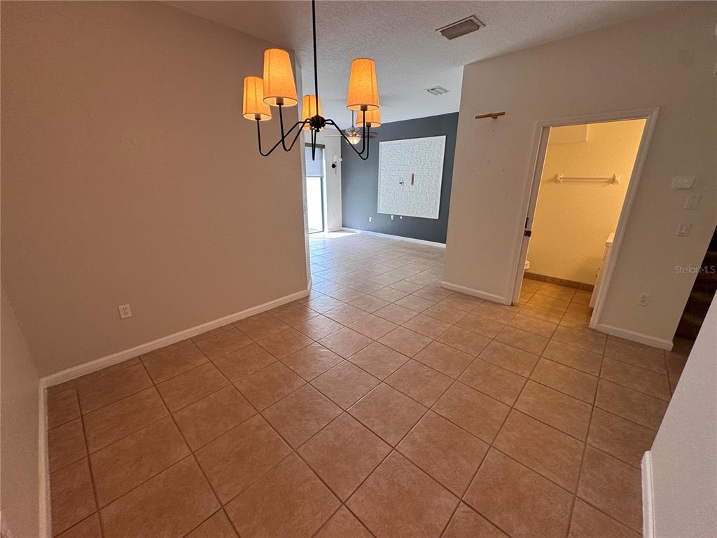 A dining area with tile flooring, a chandelier, and an adjacent doorway leading to a bathroom — 3469 ALLEGRA CIRCLE, ST CLOUD, FL